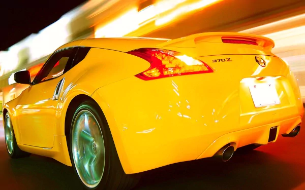 A vibrant yellow Nissan 370Z displayed in motion against a dynamic, colorful backdrop, creating an energetic and striking HD wallpaper for desktop backgrounds.