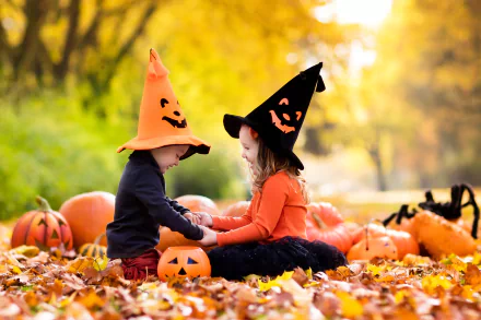 A charming fall scene featuring a little boy and girl in Halloween hats, surrounded by vibrant pumpkins and autumn leaves, capturing the joy of the holiday season.