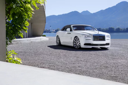 White Rolls-Royce Dawn convertible parked on a gravel surface by a modern building, with mountains and water in the background, captured in 4K Ultra HD.