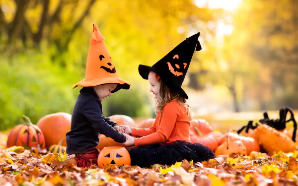 A charming fall scene featuring a little boy and girl in Halloween hats, surrounded by vibrant pumpkins and autumn leaves, capturing the joy of the holiday season.