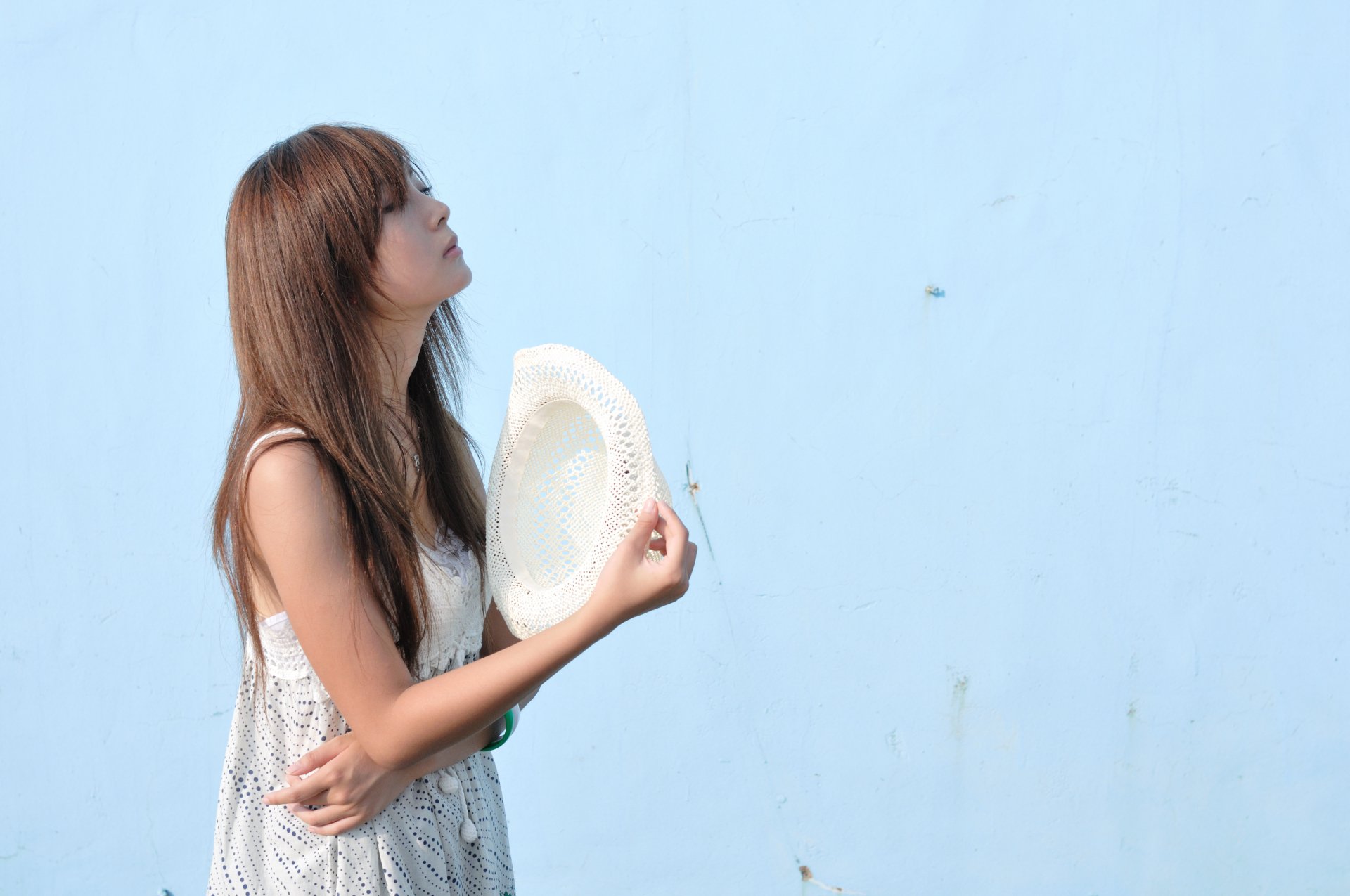 HD desktop wallpaper and background featuring Mikako Zhang Kaijie, a woman with long hair holding a hat against a light blue wall.