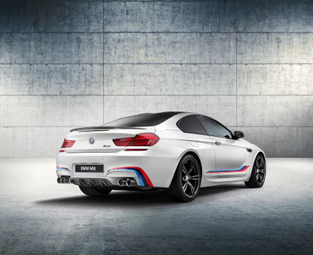White BMW M6 sports car with signature M stripes, showcased against a minimalist concrete wall background in an HD PC desktop wallpaper.