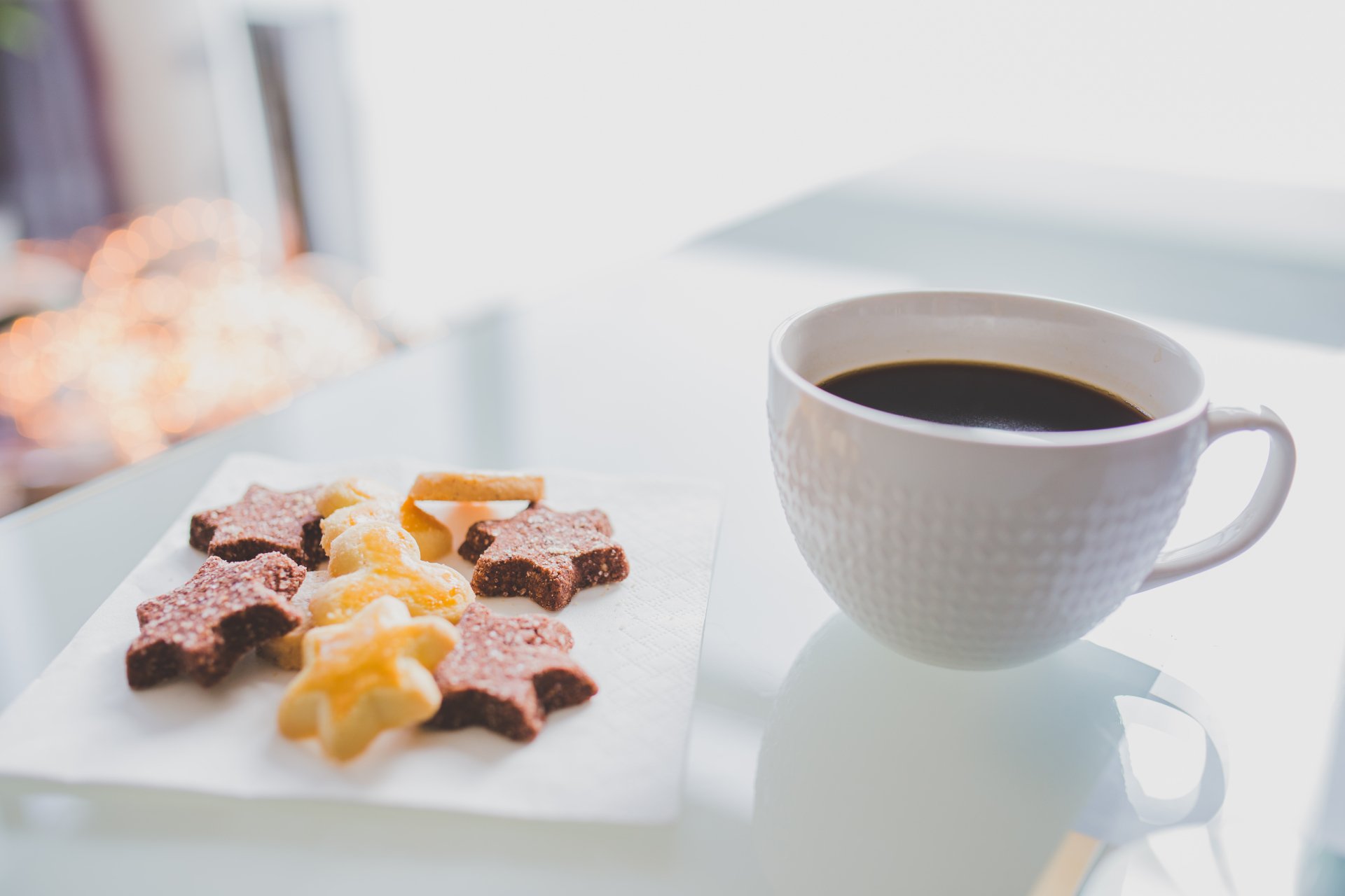 A 4K Ultra HD desktop wallpaper featuring a white cup of coffee beside star and twist-shaped biscuits on a white surface.