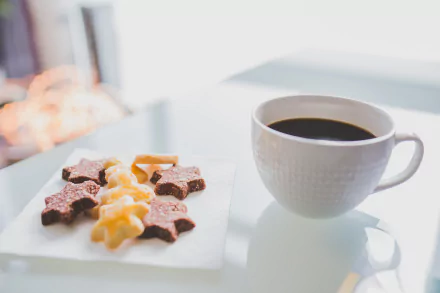 A 4K Ultra HD desktop wallpaper featuring a white cup of coffee beside star and twist-shaped biscuits on a white surface.