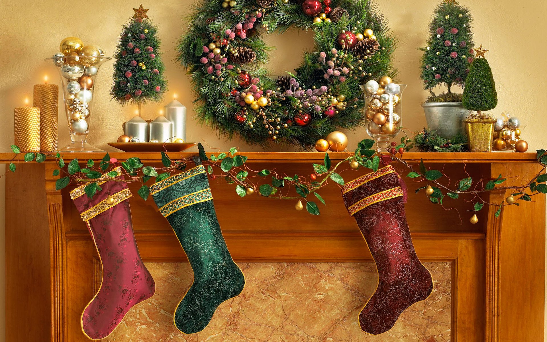 HD PC desktop wallpaper and background: Christmas holiday mantel scene with evergreen wreath, red ornaments, three stockings, candles and garland.