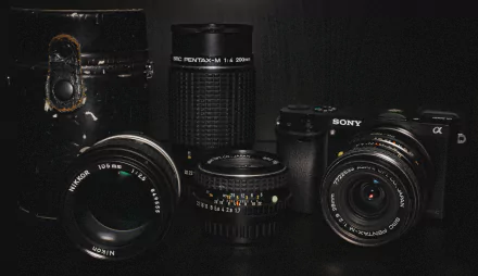 A 4K Ultra HD desktop wallpaper featuring man-made Pentax and Sony camera lenses and cameras displayed against a dark background.