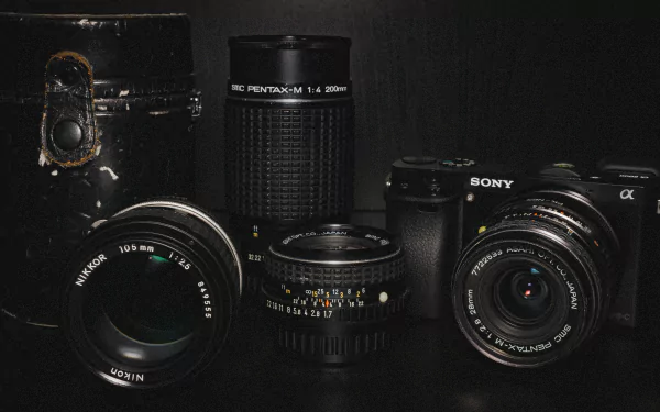 A 4K Ultra HD desktop wallpaper featuring man-made Pentax and Sony camera lenses and cameras displayed against a dark background.