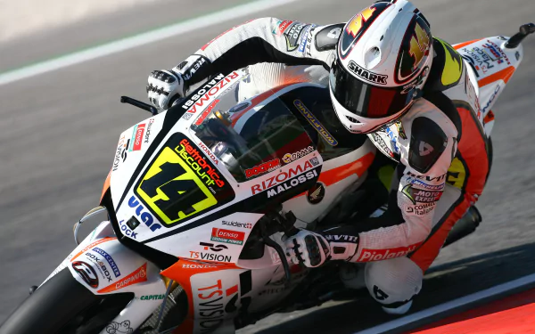 HD desktop wallpaper featuring a MotoGP racer in action, leaning into a curve at high speed. The rider is captured in detailed motion, showcasing the thrill and intensity of professional motorcycle racing.