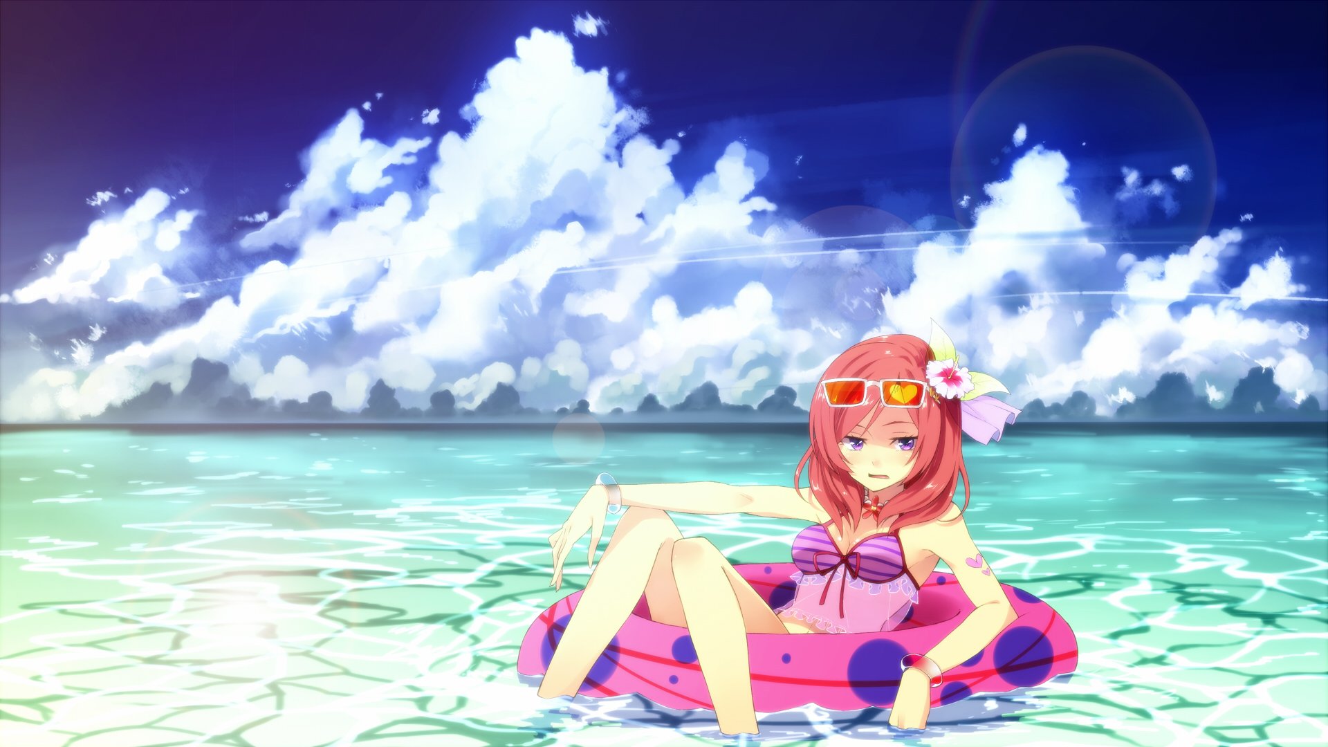 HD PC desktop wallpaper: Maki Nishikino (Love Live!) in a pink swimsuit, lounging on a donut float in clear shallow sea beneath a bright blue sky with billowing clouds.