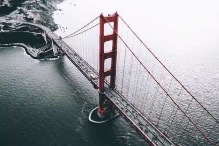 Aerial view of the iconic Golden Gate Bridge, showcasing its striking red color and surrounding waters, creating a stunning HD desktop wallpaper and background.