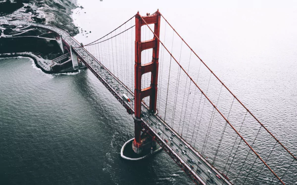Aerial view of the iconic Golden Gate Bridge, showcasing its striking red color and surrounding waters, creating a stunning HD desktop wallpaper and background.