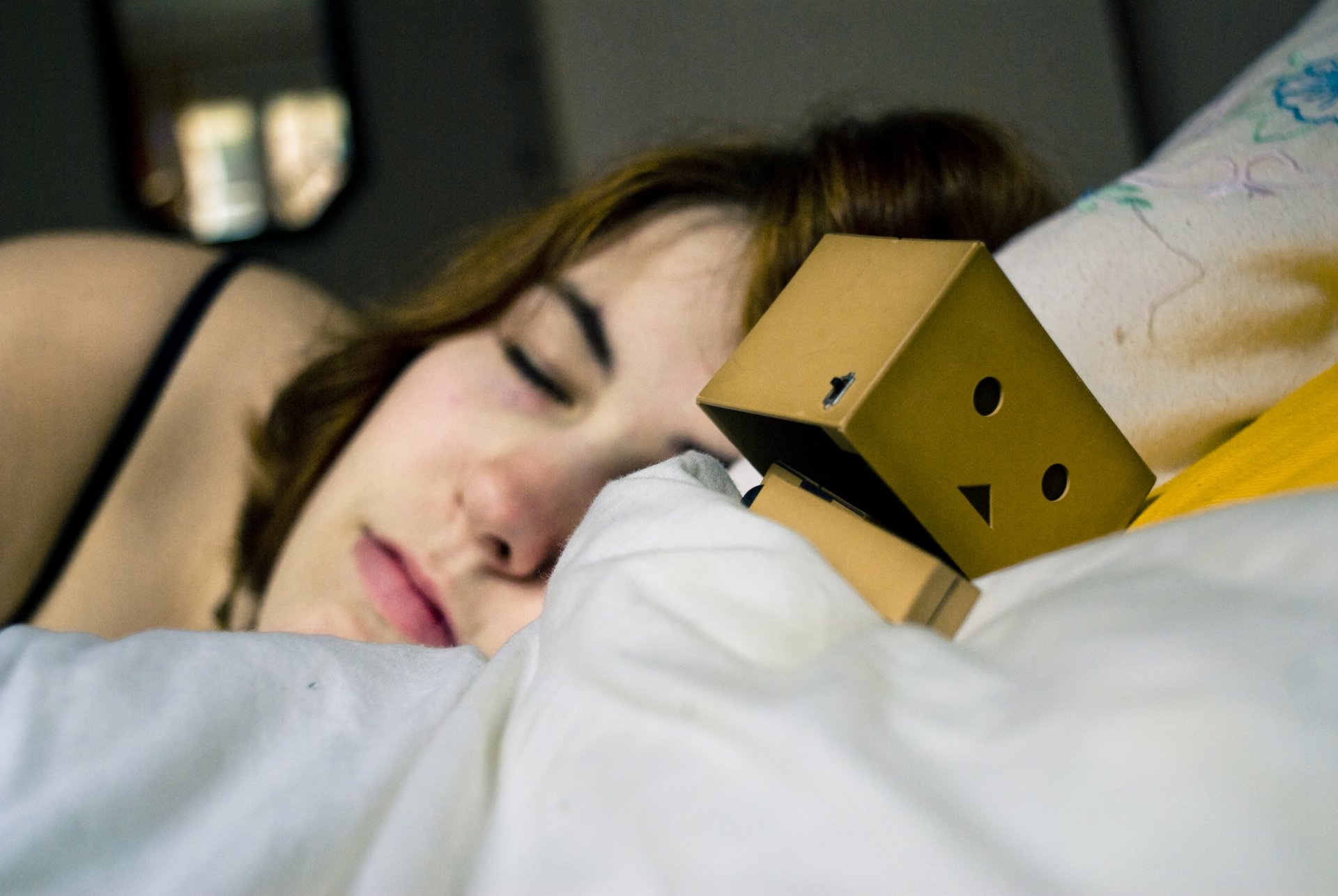 A cozy scene featuring a sleeping person beside a cute Danbo figure on a pillow, creating a warm and relaxed atmosphere, suitable as a HD PC desktop wallpaper and background.