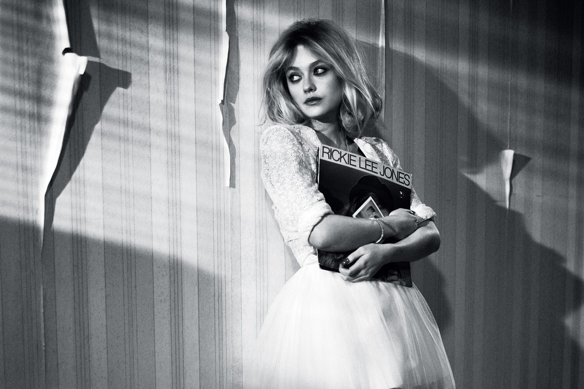 Black and white HD desktop wallpaper featuring American actress Dakota Fanning in a vintage-inspired dress holding a sign, captured in a dramatic, shadowed setting.
