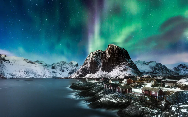 Aurora borealis lights up the night sky over the snowy mountain and Reine village in Lofoten, Norway, showcasing stunning natural beauty in this HD desktop wallpaper.