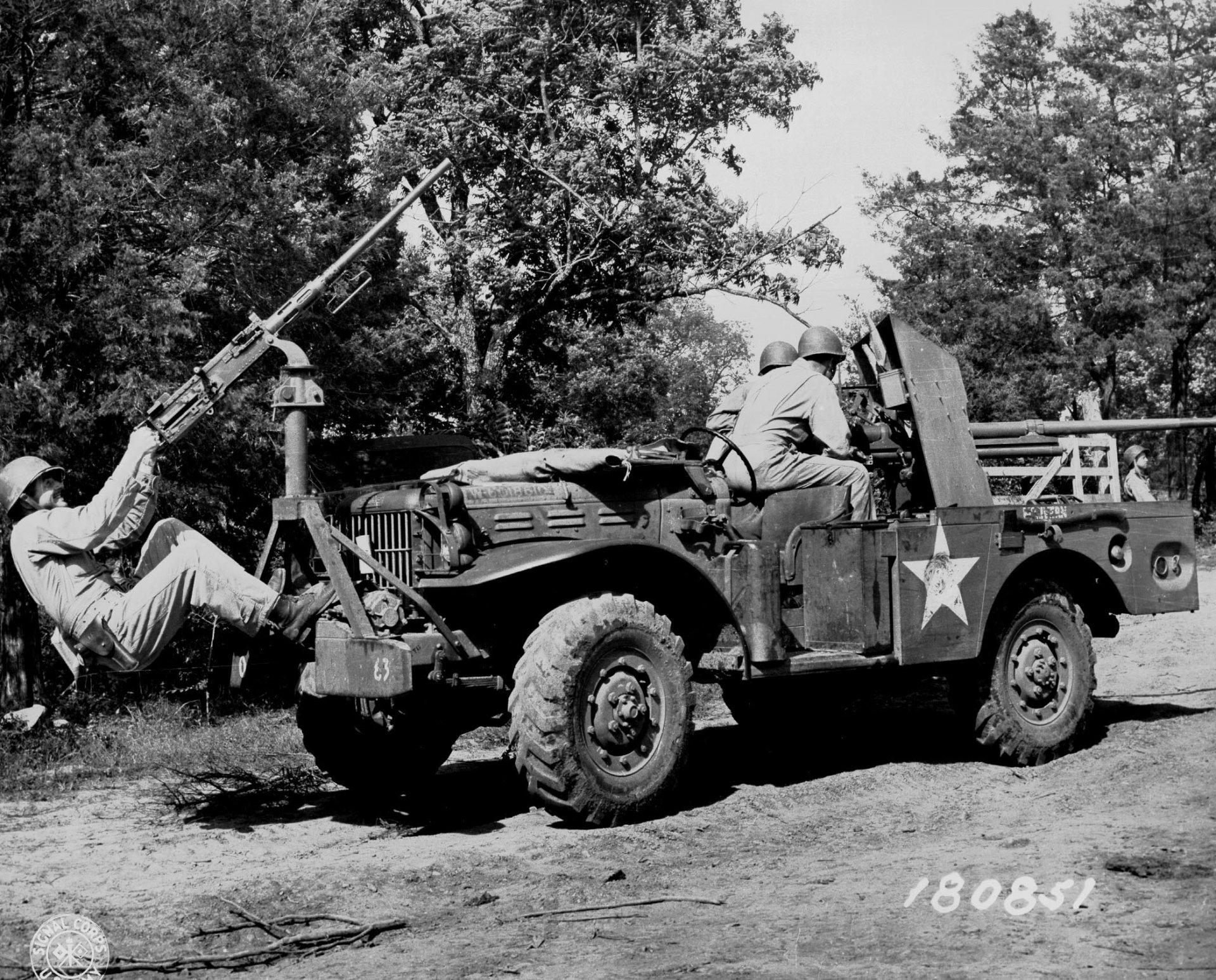 A historical black and white image of a military vehicle with soldiers, showcasing a mounted weapon, set against a wooded background. This serves as an engaging HD desktop wallpaper.