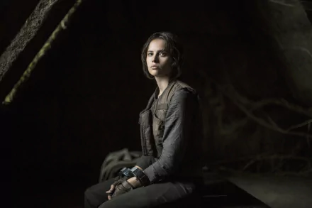 Jyn Erso, portrayed by Felicity Jones, sits contemplatively in a dark setting, capturing a moment from Rogue One: A Star Wars Story in this stunning 4K Ultra HD wallpaper.