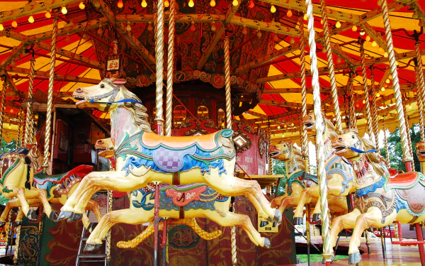 HD desktop wallpaper featuring a colorful man-made carousel with ornate horse figures on a merry-go-round, illuminated by warm lights.
