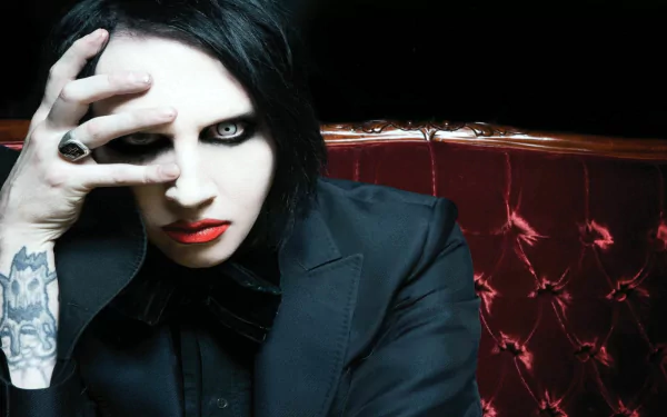 HD PC desktop wallpaper: industrial/heavy metal musician with pale makeup and black hair, red tufted leather backdrop, moody gothic aesthetic and intense, theatrical stare.