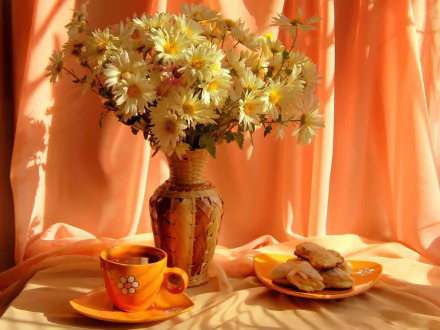 Still life photography of daisies in a vase beside a plate of cookies and a matching cup, set against warm orange drapes, featured as an HD PC desktop wallpaper.
