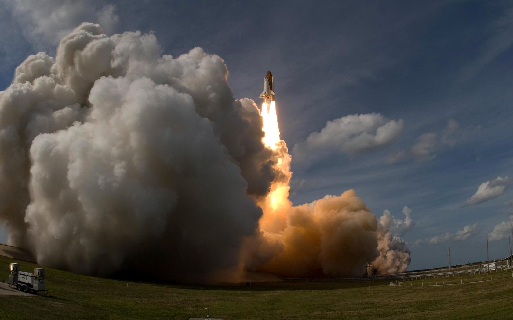A dynamic HD wallpaper featuring a space shuttle launching into the sky, surrounded by billowing clouds and engine flames, capturing the excitement of space exploration.