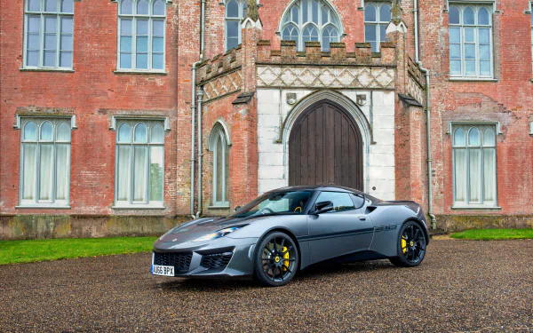 Silver Lotus Evora Sport 410 supercar parked in front of a historic brick building, captured in stunning 4K Ultra HD for a PC desktop wallpaper and background.