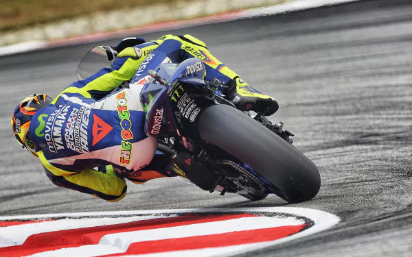 HD desktop wallpaper featuring a thrilling MotoGP race scene with a motorcyclist leaning into a sharp turn on a race track.