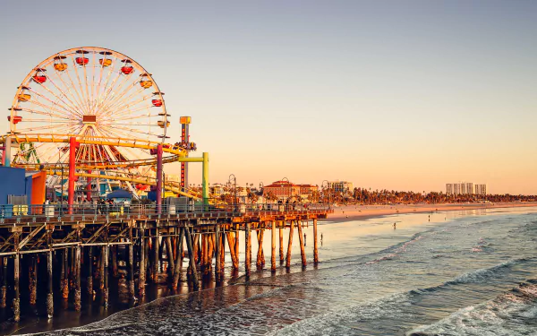 HD desktop wallpaper of Santa Monica Pier amusement park with a vibrant Ferris wheel overlooking the beach at sunset in Los Angeles, California, USA.