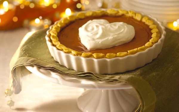 HD desktop wallpaper of a sweet pie with heart-shaped whipped cream topping on a cake stand, set against a background of twinkling lights.