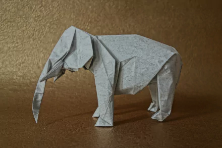 Origami elephant, man-made paper sculpture on a textured gold surface, shown as a 5K Ultra HD PC desktop wallpaper and background.