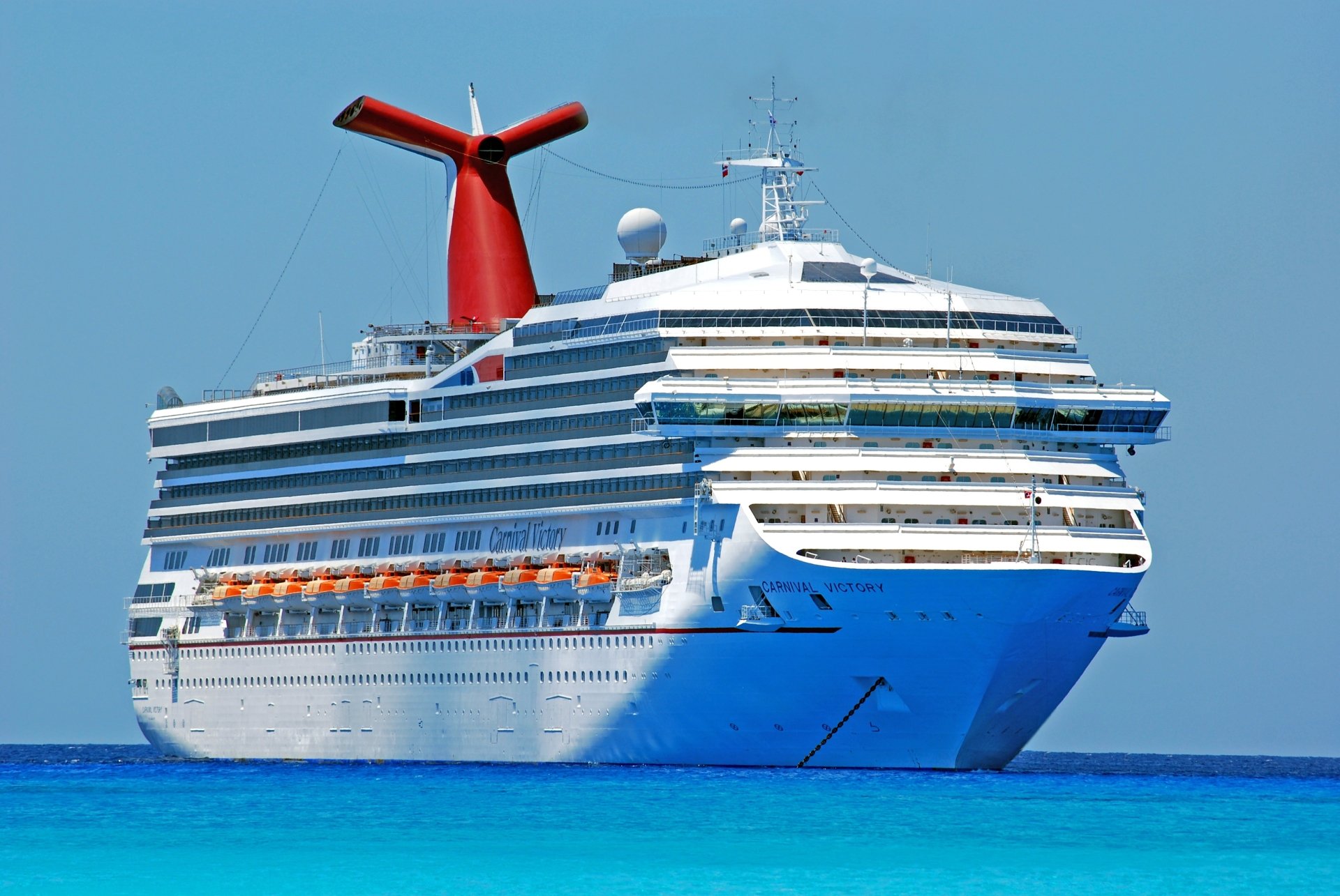 4K Ultra HD image of the Carnival Victory cruise ship sailing on clear blue waters, showcasing its distinctive red funnel and multiple decks.