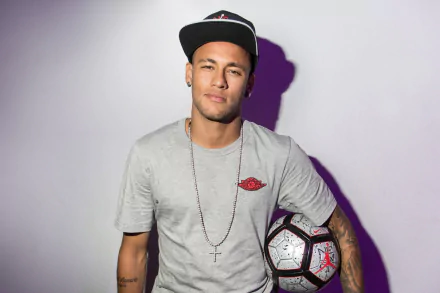 HD desktop wallpaper featuring Brazilian soccer player Neymar, dressed casually with a soccer ball and a cap. The calm background highlights his relaxed stance and passion for the sport.