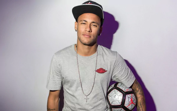 HD desktop wallpaper featuring Brazilian soccer player Neymar, dressed casually with a soccer ball and a cap. The calm background highlights his relaxed stance and passion for the sport.