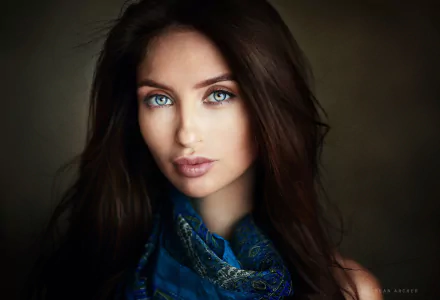 Close-up portrait of a brunette woman with striking blue eyes, captured in HD quality, designed as a PC desktop wallpaper background.