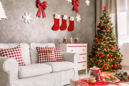 Cozy living room with a white sofa, plaid pillows, decorated Christmas tree, red stockings, and holiday ornaments creating a festive 4K Ultra HD desktop wallpaper.