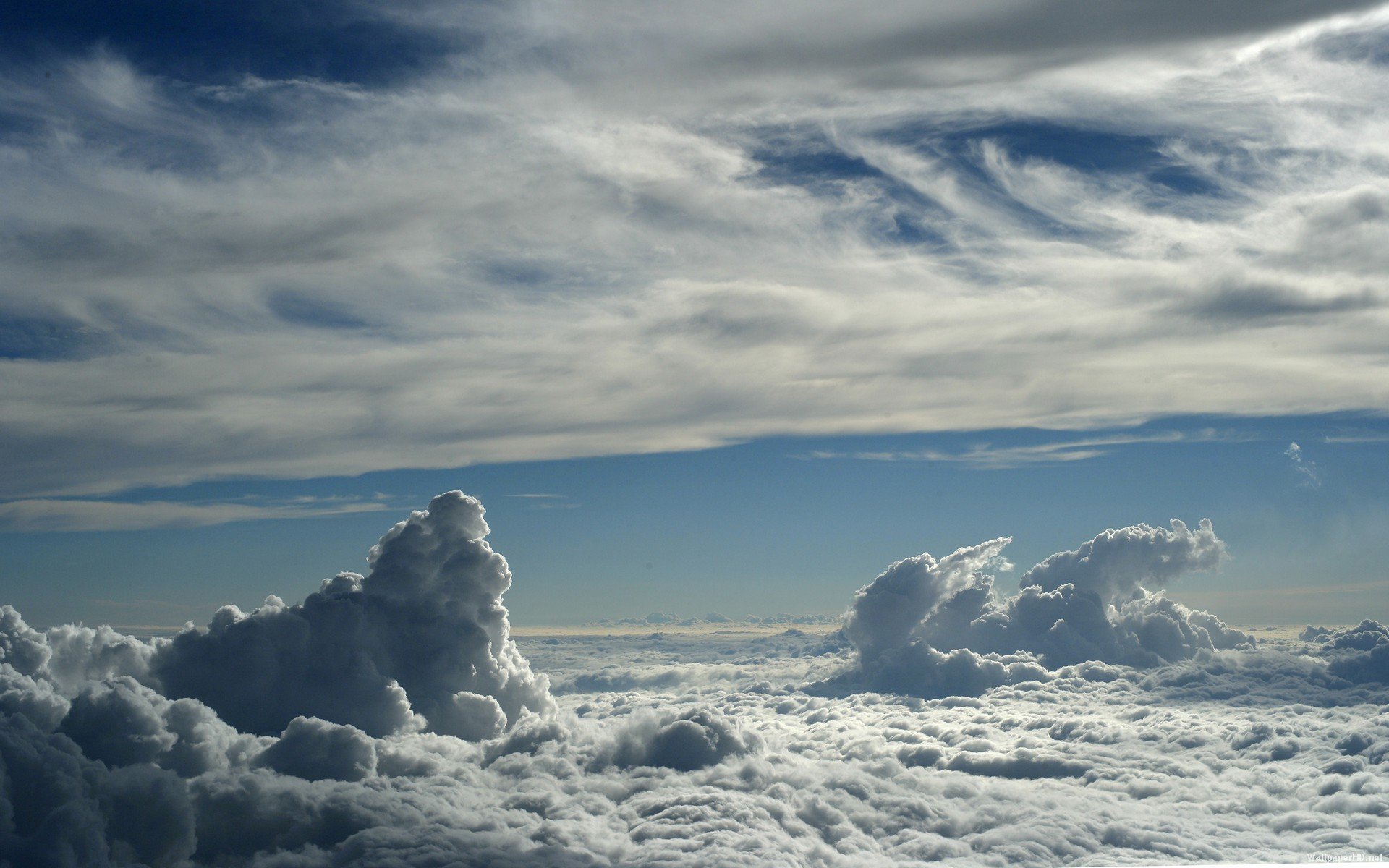 Aerial view of puffy white clouds under a serene blue sky for HD desktop wallpaper.