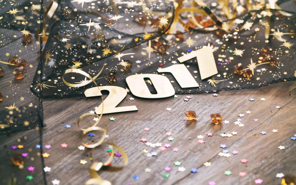 Golden confetti and the numbers 2017 adorn a festive New Year holiday background in this HD desktop wallpaper.