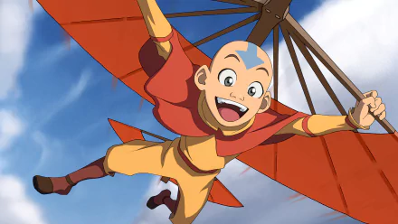 HD desktop wallpaper of Aang from Avatar: The Last Airbender flying with a glider, smiling widely. He has grey eyes, and the clear sky is visible in the background.