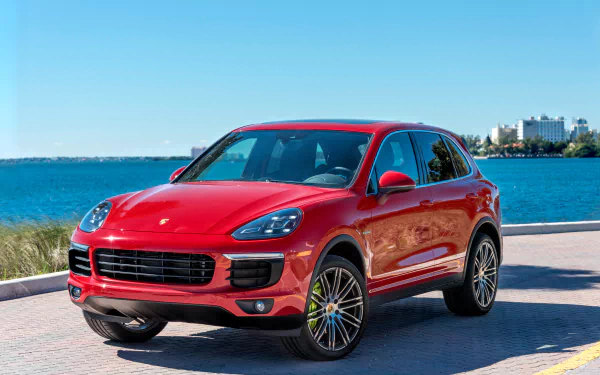 Red Porsche Cayenne SUV parked by the waterfront under clear blue skies, captured in 4K Ultra HD quality for a PC desktop wallpaper.