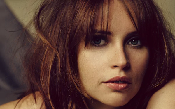 Close-up portrait of English actress Felicity Jones with brunette hair and green eyes, featured in an HD PC desktop wallpaper and background.