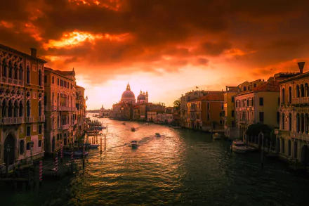 Sunset over the Grand Canal in Venice, Italy, with boats gliding through the water and historic buildings lining the cityscape under dramatic clouds.