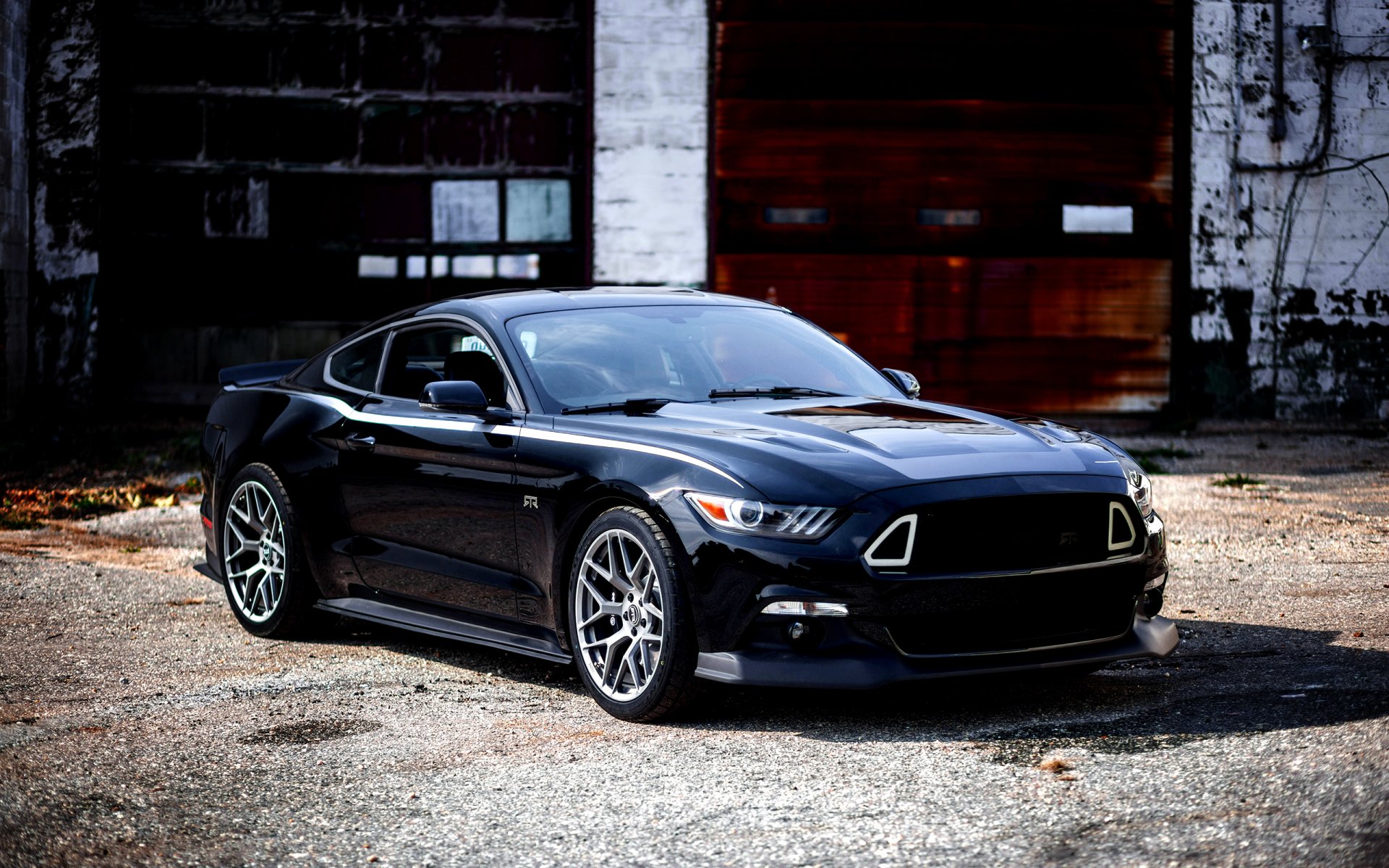 Black Ford Mustang RTR muscle car parked in front of an industrial building, showcased as a high-definition PC desktop wallpaper and background.