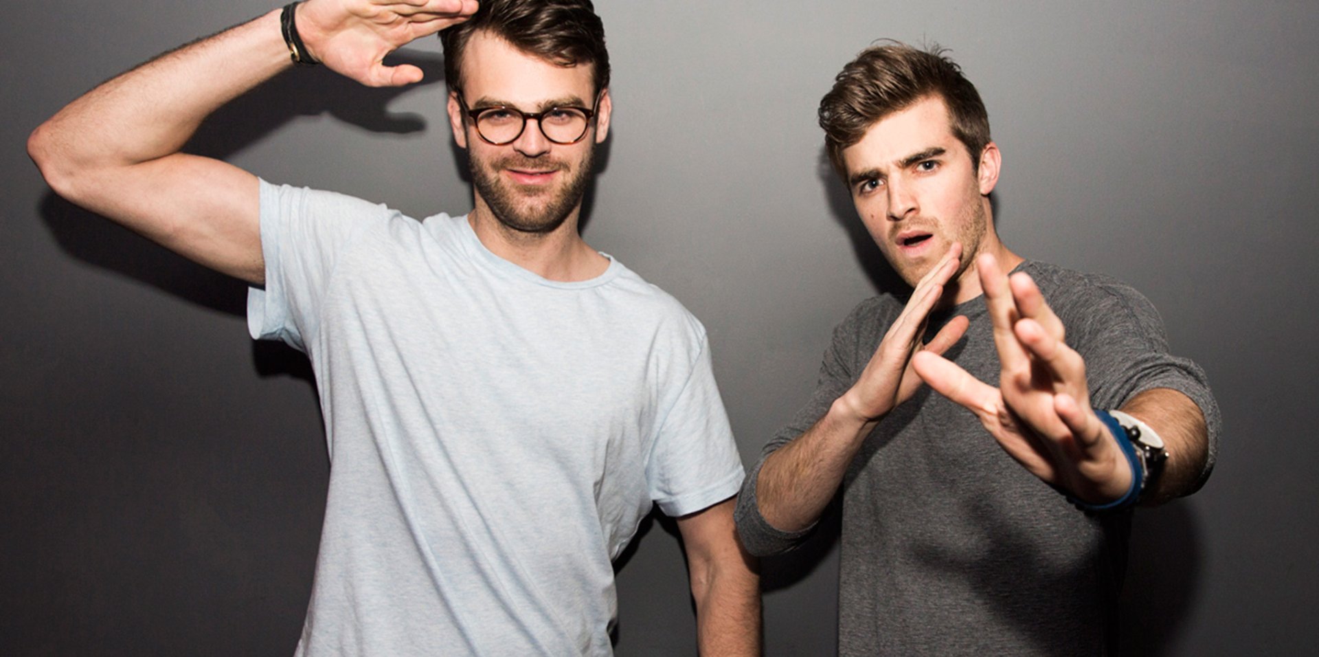 HD desktop wallpaper featuring The Chainsmokers posing with playful hand gestures against a gray background.