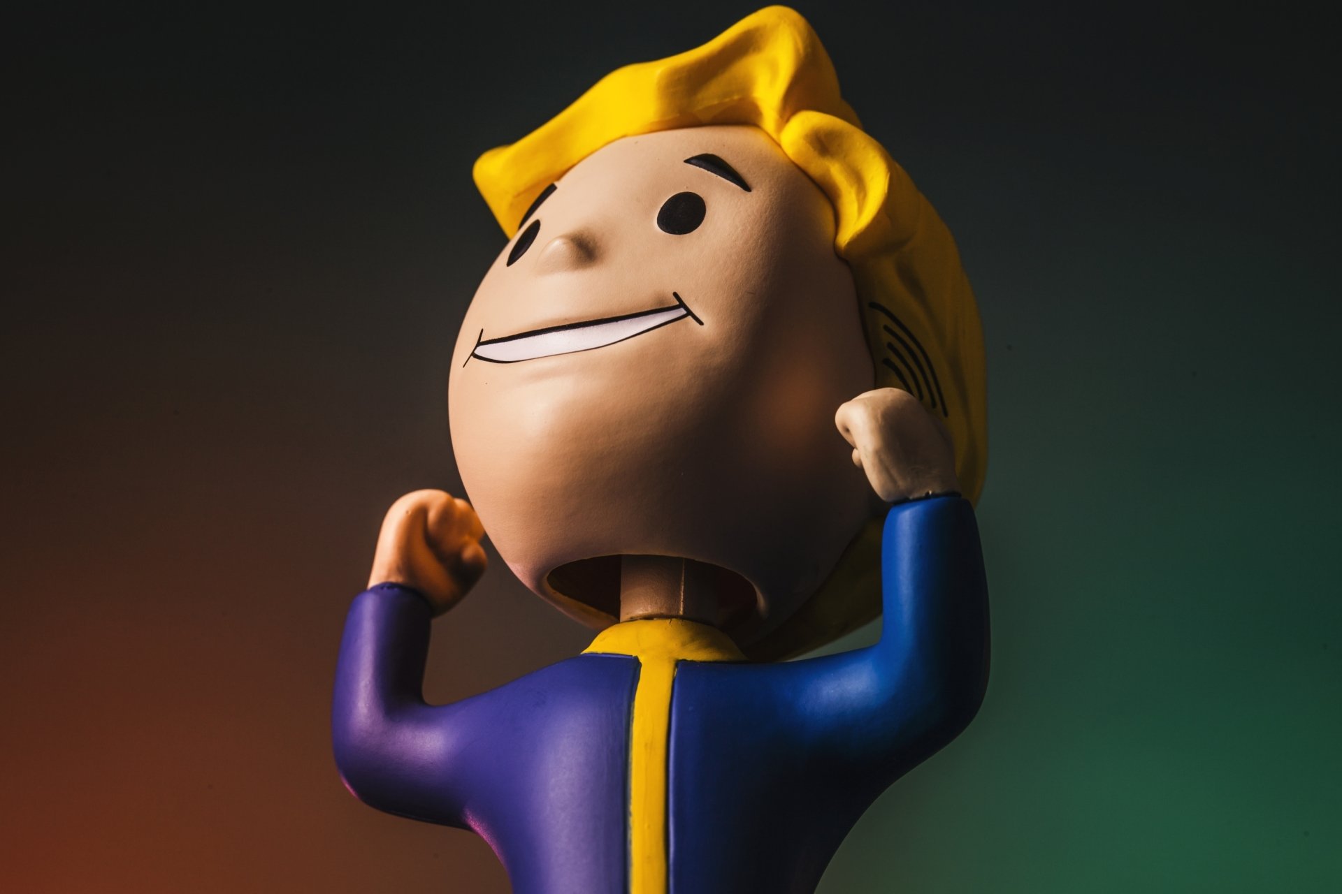 HD PC desktop wallpaper of a Vault Boy figurine from the Fallout video game, grinning and flexing against a dramatic gradient background.