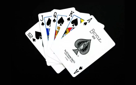 A close-up image of a straight flush in spades from a Bicycle deck of cards. The cards are neatly fanned out against a black background, making a striking HD desktop wallpaper.