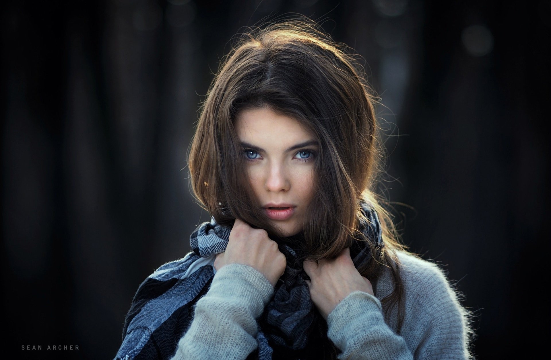 HD desktop wallpaper featuring a brunette woman with striking blue eyes, captured in a moody, high-definition portrait.