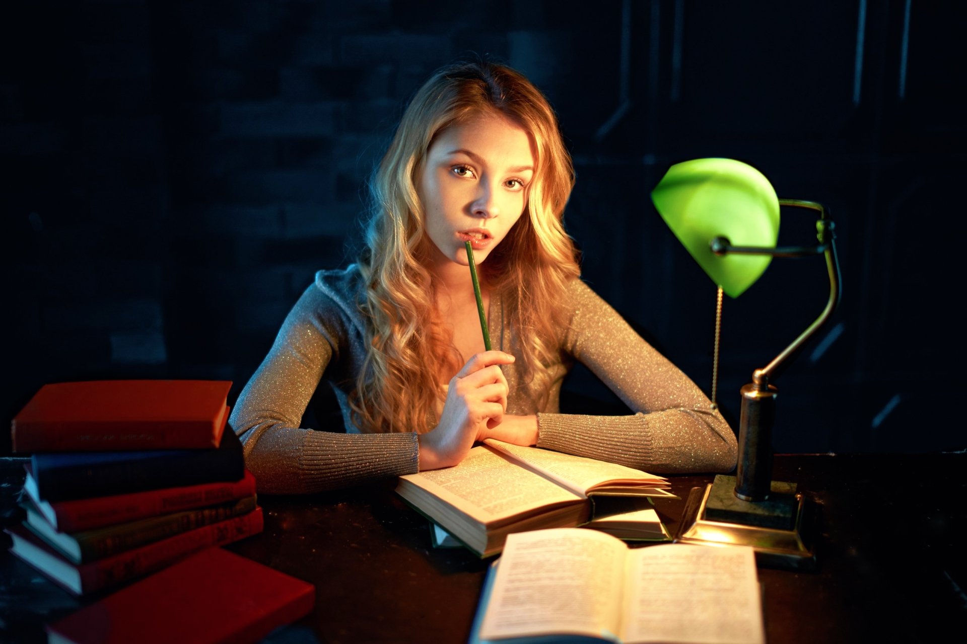 Blonde woman with hazel eyes, Alice Tarasenko, sits at a desk reading a book under a green lamp in this HD PC desktop wallpaper and background.