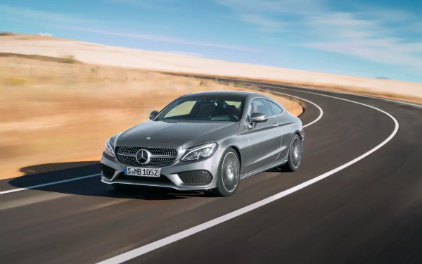 Silver Mercedes-Benz C-Class car driving on a curved road, captured in a sharp 4K Ultra HD desktop wallpaper background.