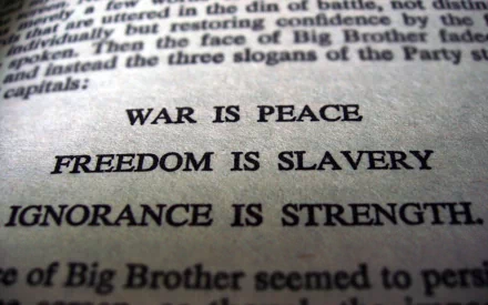 Black and white HD wallpaper featuring a close-up of the slogans from George Orwell's Nineteen Eighty-Four: War is peace, freedom is slavery, ignorance is strength.