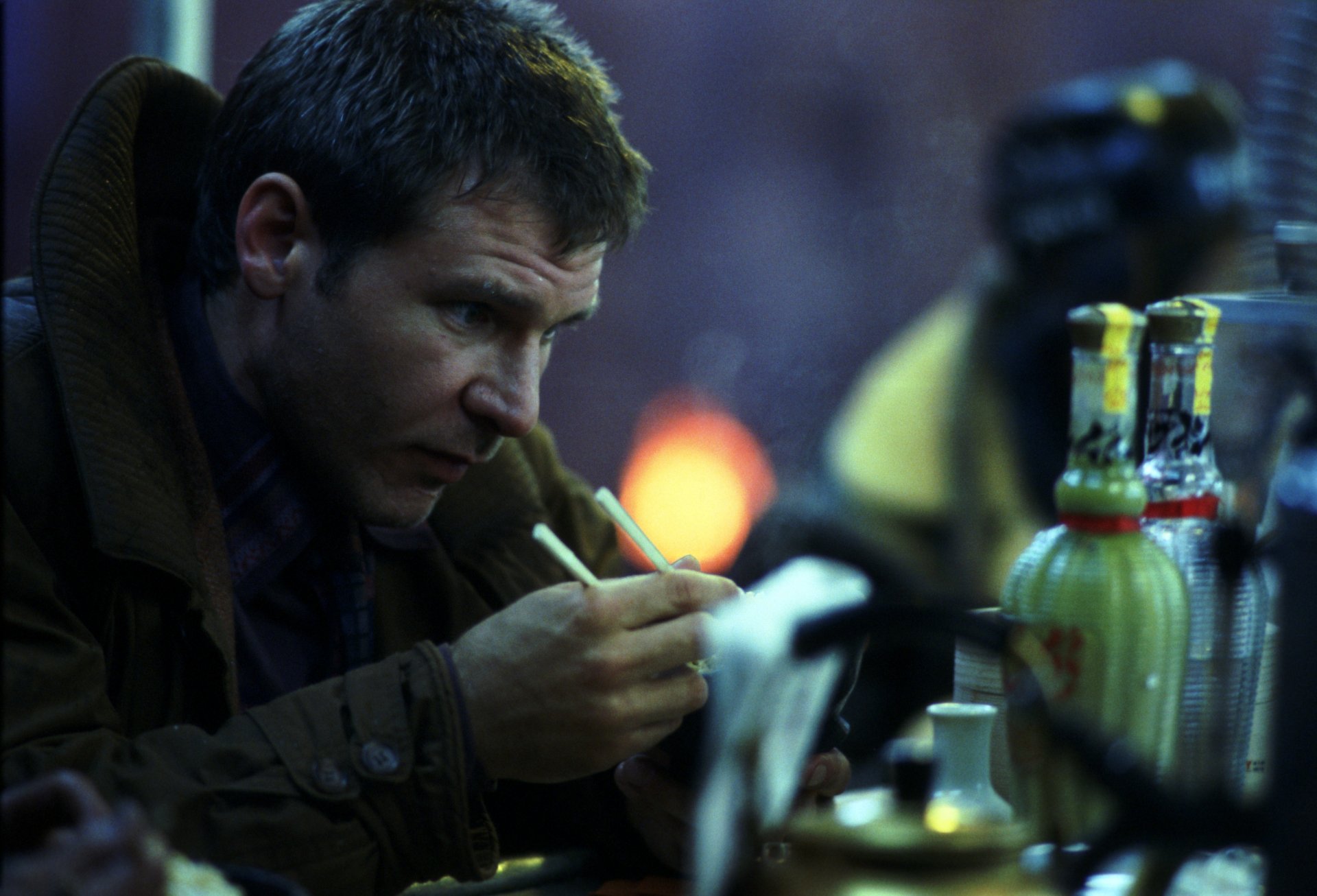 HD PC desktop wallpaper featuring a moody scene from the movie Blade Runner with a man intently lighting a cigarette in a dimly lit setting.