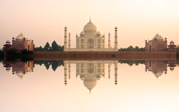 HD desktop wallpaper showing the Taj Mahal, an iconic monument in India, with its domed architecture and surrounding buildings reflected beautifully in serene water at dawn or dusk.